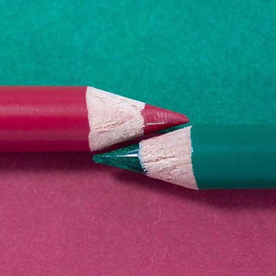 Deux crayons de couleur pourpre et émeraude qui se font face sur une surface divisée dans les deux couleurs